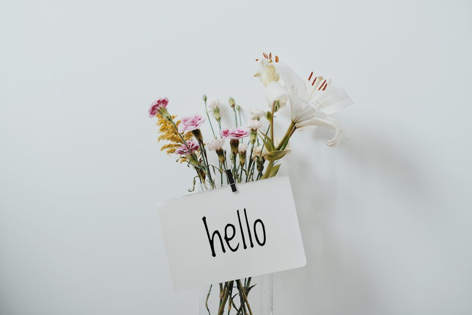 A colorful bouquet of wildflowers with a greeting card saying 'hello' on a simple background.