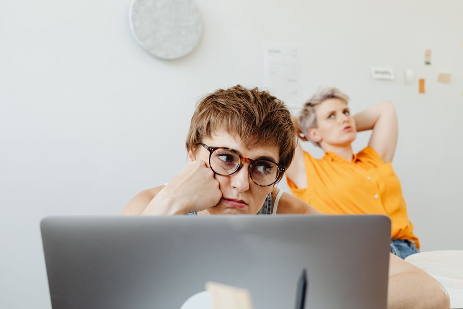 Two women in a home office setting, focused on work while using a laptop.