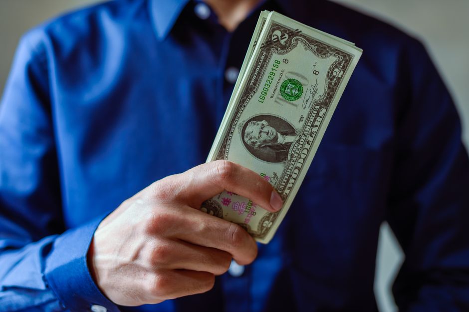 Close-up of a person holding two dollar bills, representing wealth and finance.