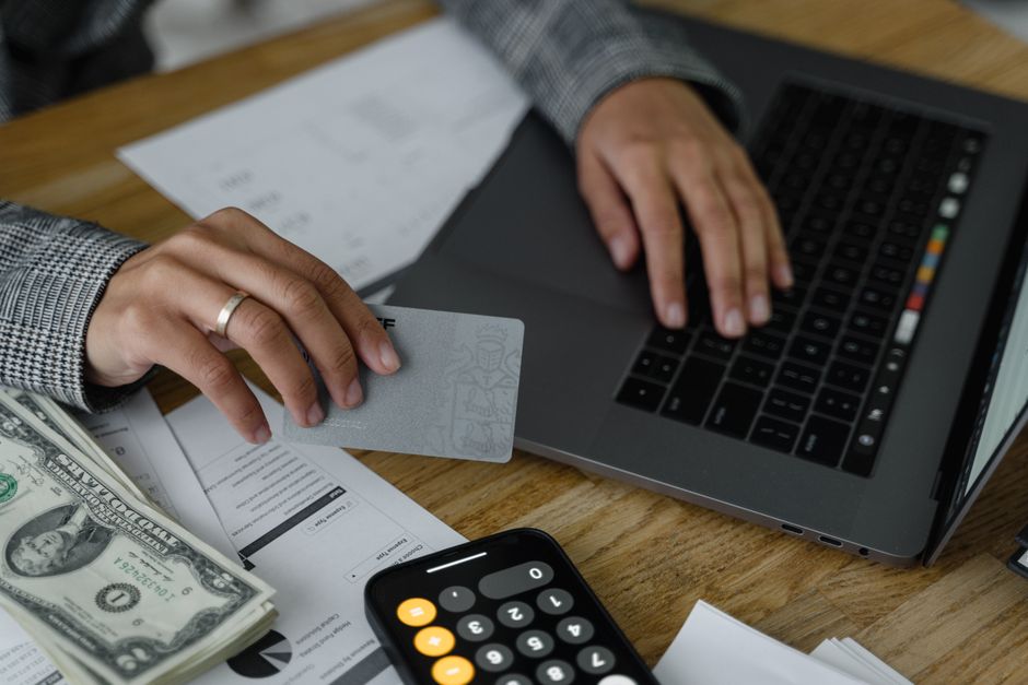 Setting up automatic loan payments on a laptop with a calculator and bills