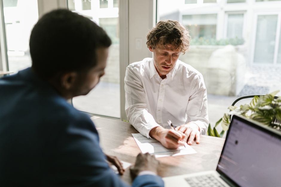 Two people reviewing and signing loan documents in an office
